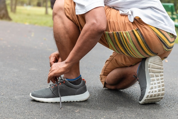 Portrait of senior Asian sports man tying shoelaces on the road.