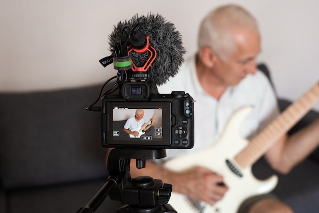 Portrait of senior blogger playing guitar from his home recording studio