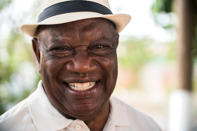 portrait of senior brazilian black man with white hat looking at camera spot in sunset and smiling. Horizontal shape, copy space.