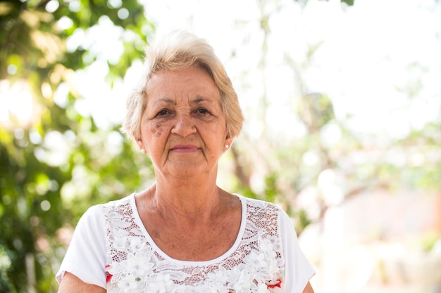 Photo portrait of senior brazilian woman looking at camera in sunset and smiling. horizontal shape, copy space