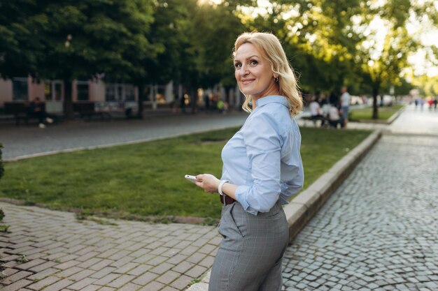 Portrait of senior business woman using smartphone in the city Cheerful mature business woman in classic wear