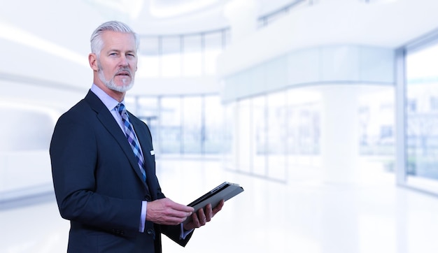 Portrait of senior businessman using tablet in front of his modern office