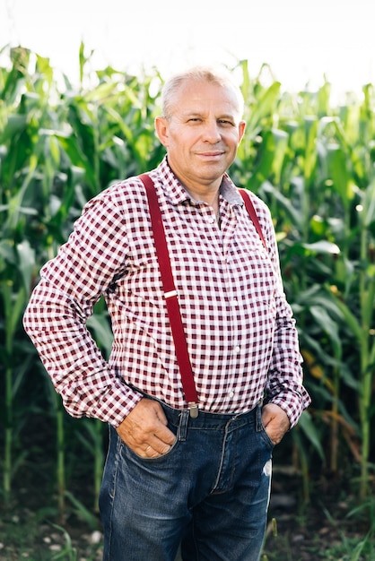 Портрет старшего кавказского красивого счастливого фермера, стоящего в кукурузном поле и улыбающегося камере