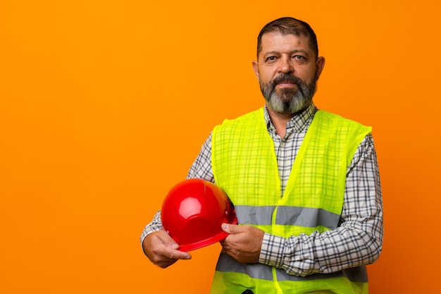 Portrait of senior construction worker in yellow vest in studio