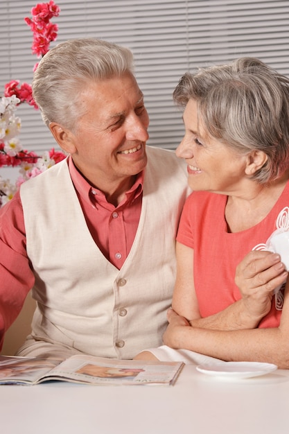 Portrait of senior couple reading magazine at home