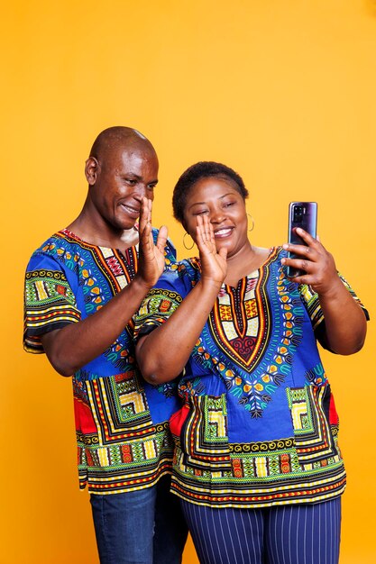 Portrait of senior couple standing against yellow background