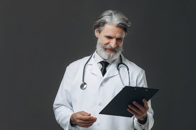 Portrait of senior doctor holding clipboard in his hands