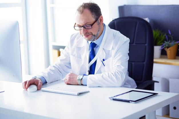 Portrait of senior doctor in office sitting at the desk