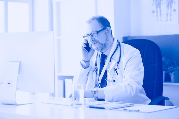 Portrait of senior doctor in office sitting at the desk