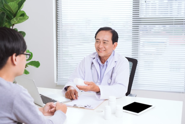 Portrait of senior doctor sitting at his desk in medical office