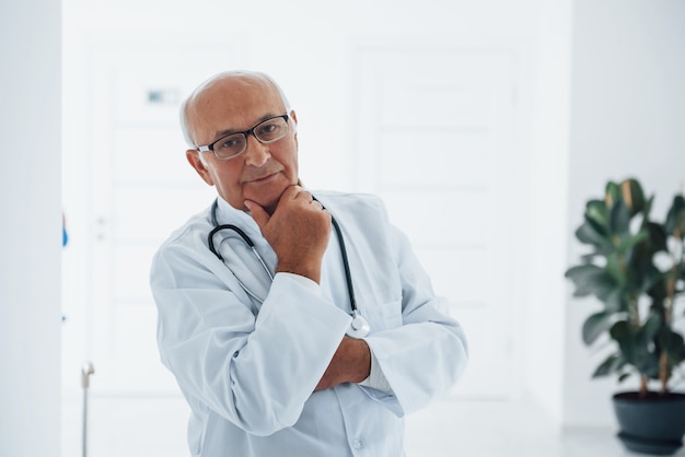 Портрет старшего врача в белой форме, стоящего в клинике.