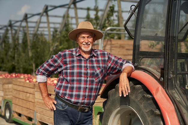 Foto ritratto di un agricoltore anziano accanto al trattore