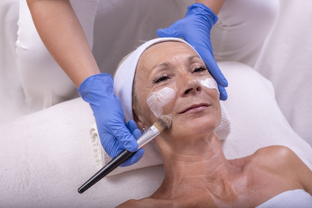 Photo portrait of a senior female getting an anti-aging treatment with derma roller