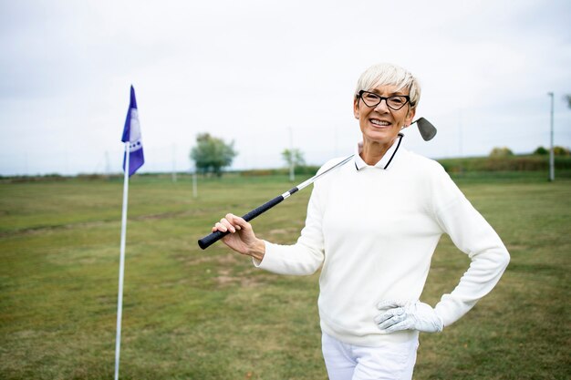 Ritratto del giocatore di golf femminile senior che gode della sua pensione giocando a golf.