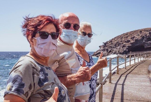 Photo portrait of senior friends by sea against sky