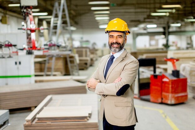 Portrait of senior  handsome businessman in suit with helmet in a warehouse