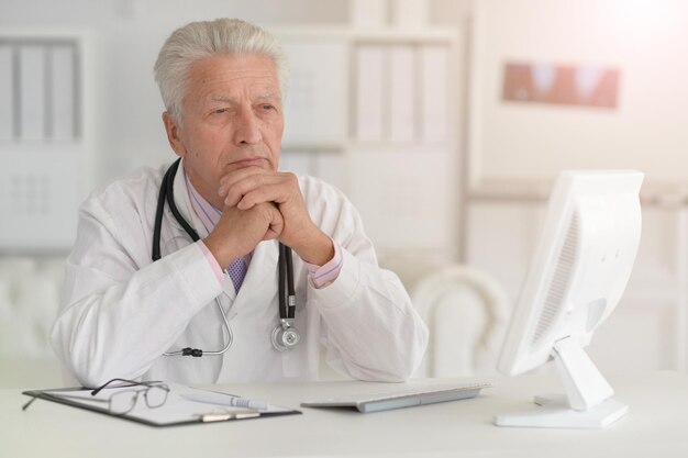 Portrait of senior male doctor working with laptop