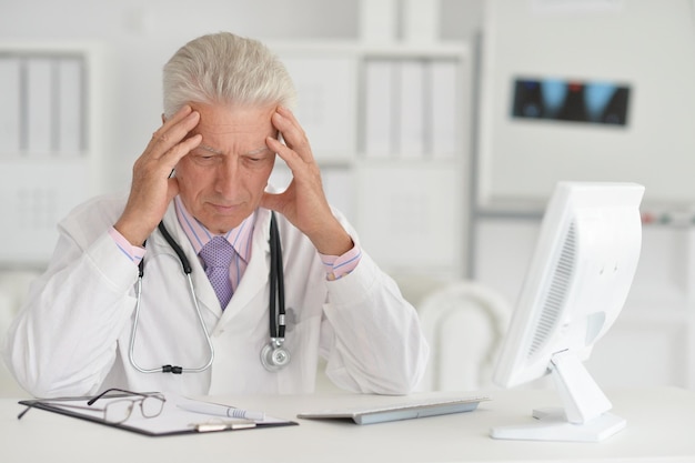 Photo portrait of senior male doctor working with laptop