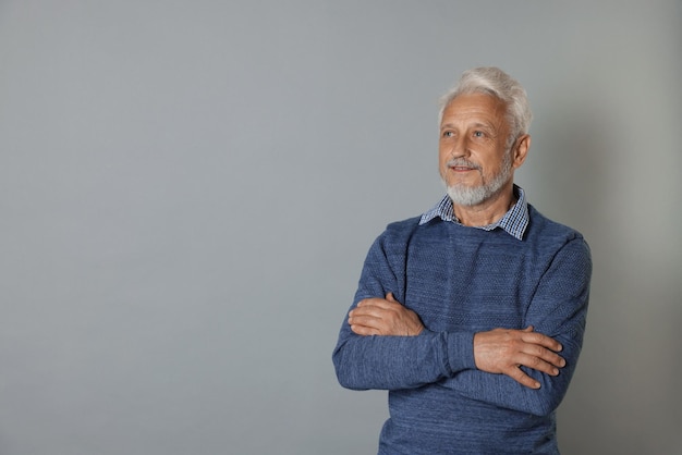 Portrait of senior man on grey background space for text