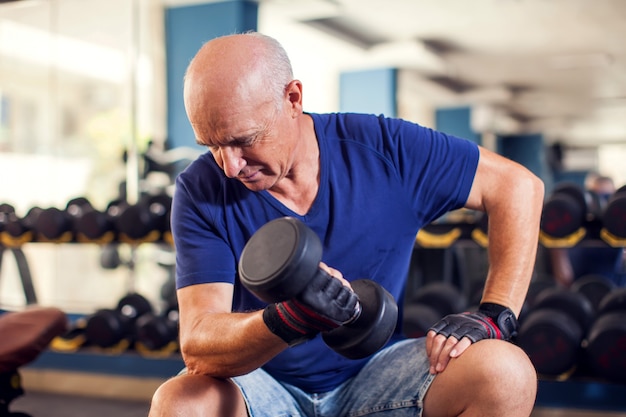 ダンベルでジムのトレーニングで年配の男性の肖像画。人、健康、ライフスタイルのコンセプト