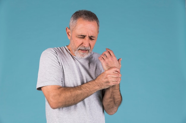 Photo portrait of a senior man holding his injured wrist