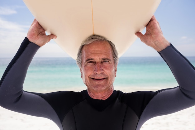 Portrait of senior man holding a surfboard over his head