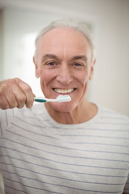 Portrait of senior man holding toothbrush in bathroom