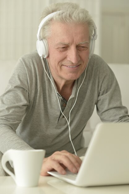 Portrait of  senior man  in the kitchen at home with laptop