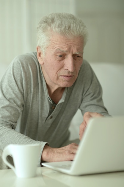 Portrait of  senior man  in the kitchen at home with laptop