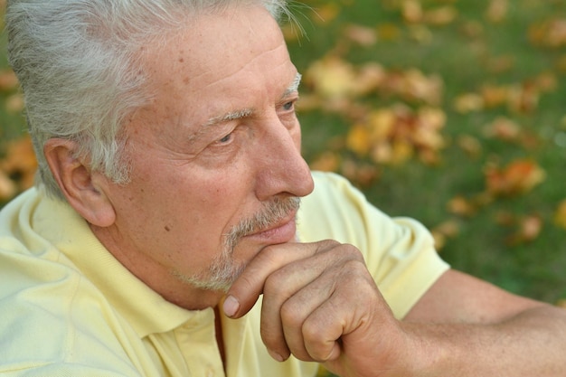 Portrait of senior man in park sitting on the grass