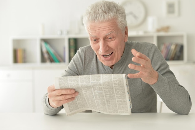 Portrait of senior man reading newspaper at home