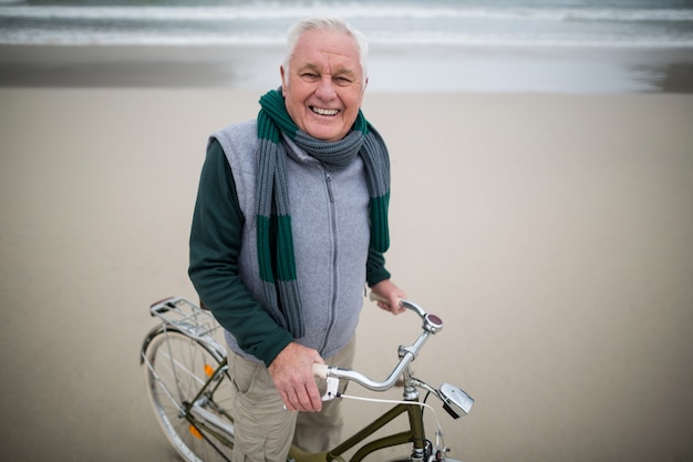 Photo portrait of senior man riding bicycle on the beach