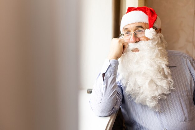 portrait of senior man in santa hat looking at camera