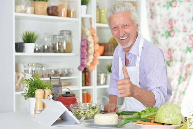 キッチンで夕食を準備しながら親指を現して年配の男性の肖像画