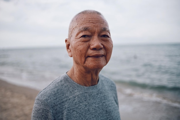 Portrait of senior man standing at beach against sky during sunset