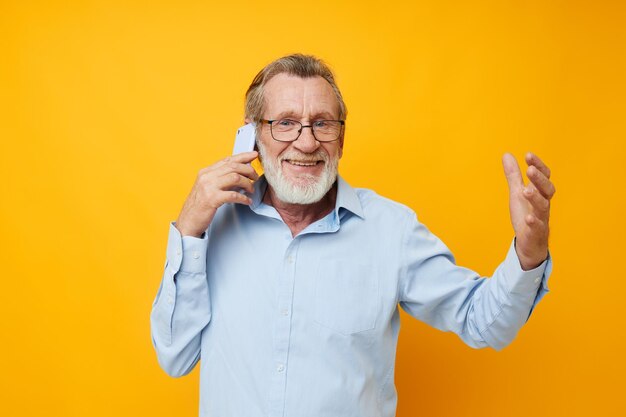 Portrait of senior man talking on phone against yellow background