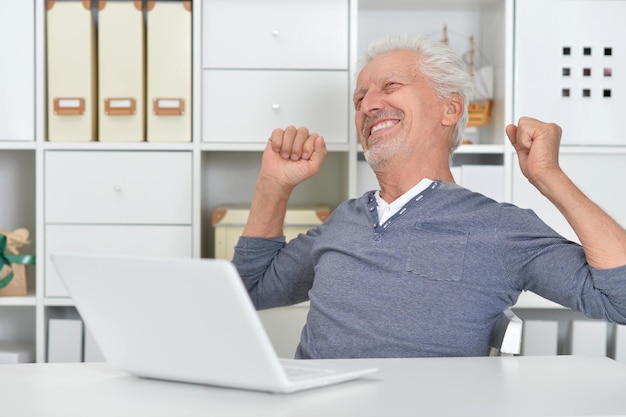 Portrait of senior man using laptop at home