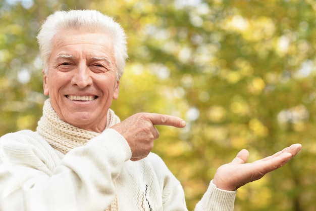 Photo portrait of a senior man on a walk pointing at something