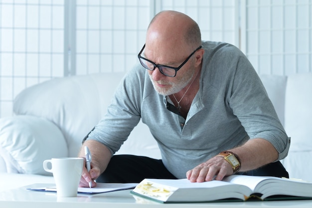 Portrait of senior man with book at home