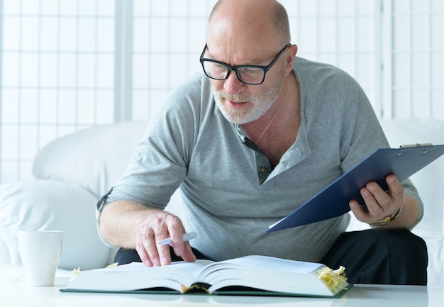 Portrait of senior man with book at home