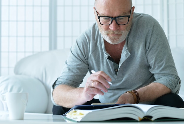 Portrait of senior man with book at home