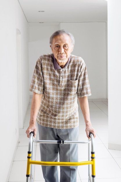 Portrait of senior man with mobility walker standing at home