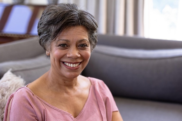 Portrait of a senior mixed race woman enjoying her time at home, sitting on a couch, looking at camera, social distancing and self isolation in quarantine lockdown during coronavirus covid19 epidemic