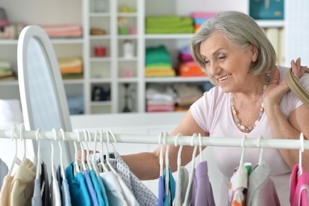 Portrait of senior woman choosing shirt in shop