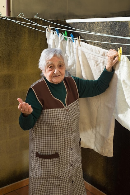 Foto ritratto di una donna anziana che asciuga i vestiti all'aperto