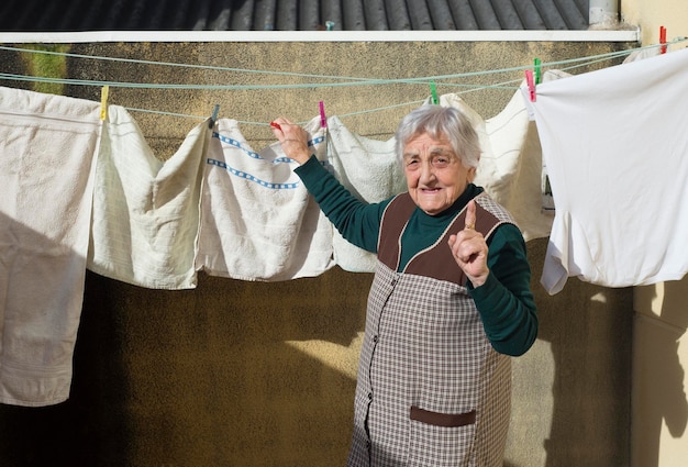 Foto ritratto di una donna anziana che asciuga i vestiti all'aperto