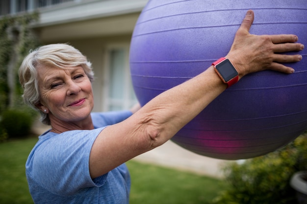 Portrait of senior woman exercising with fitness ball