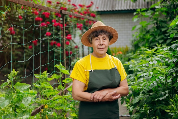 Portrait of a Senior woman gardener in a hat working in her yard The concept of gardening growing and caring for flowers and plants