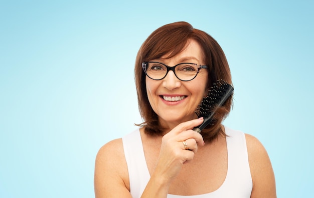 портрет пожилой женщины в очках, чистящей волосы