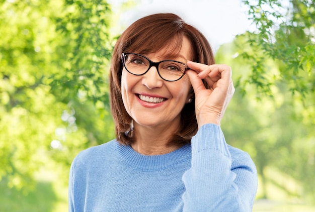 Photo portrait of senior woman in glasses over grey